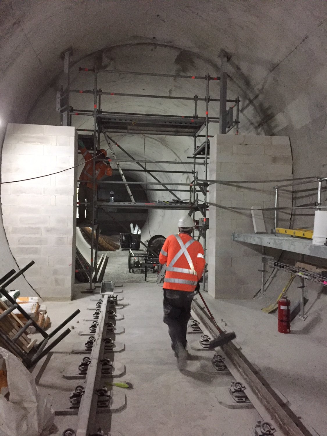 Trackform slab and rail fastenings inside the running tunnel, with blockwork at the cross-passage opening