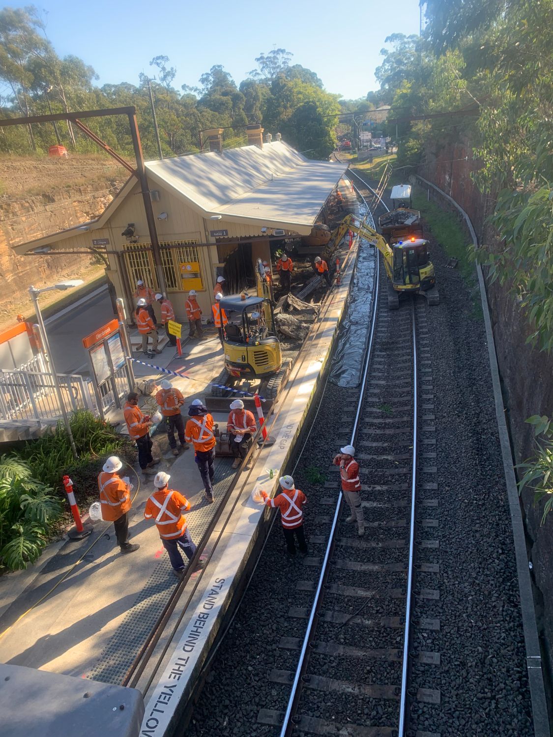 Platform works under possession, with crew and excavators alongside the live track