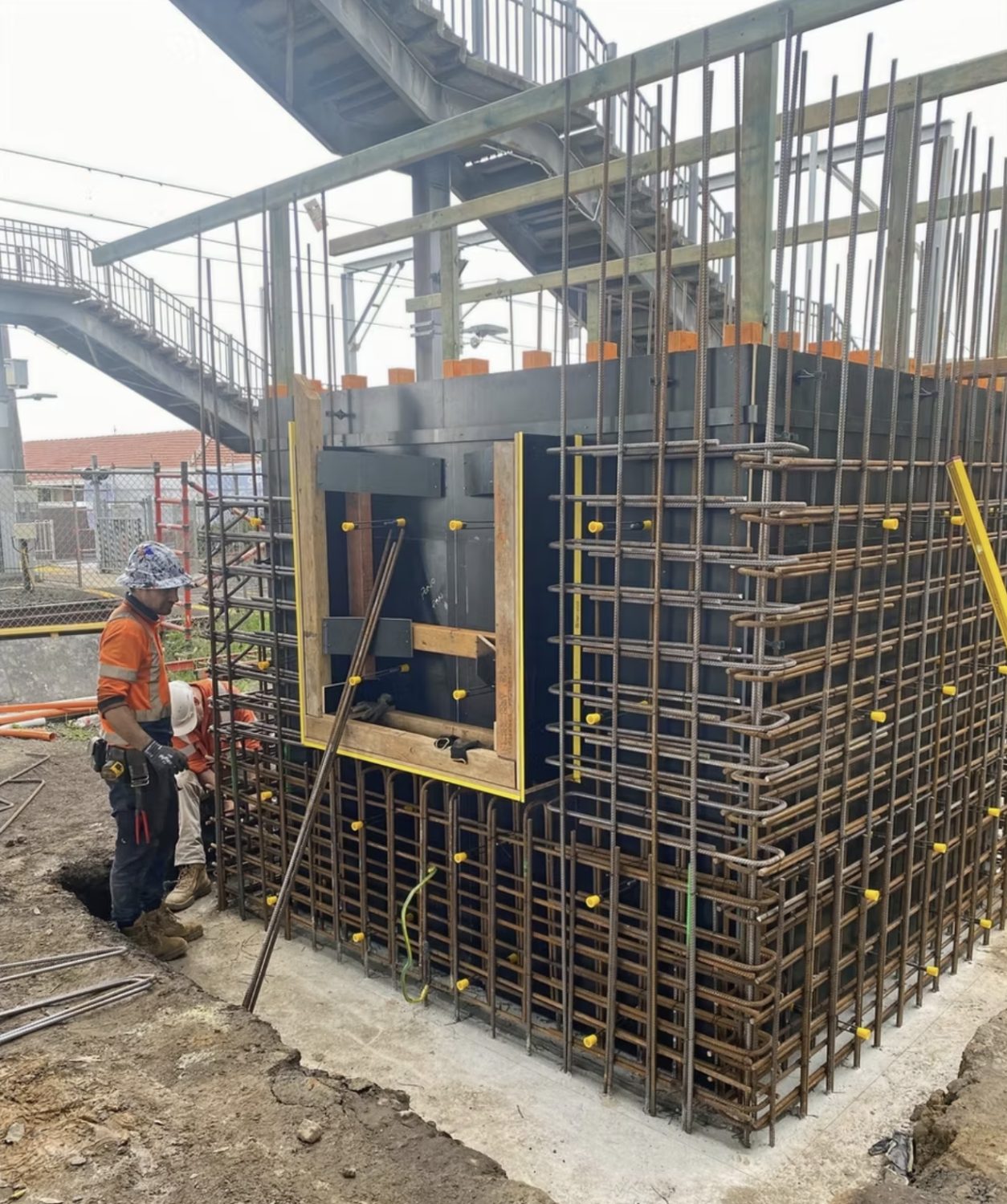 Lift shaft wall formwork and reinforcement under the existing footbridge, with crew