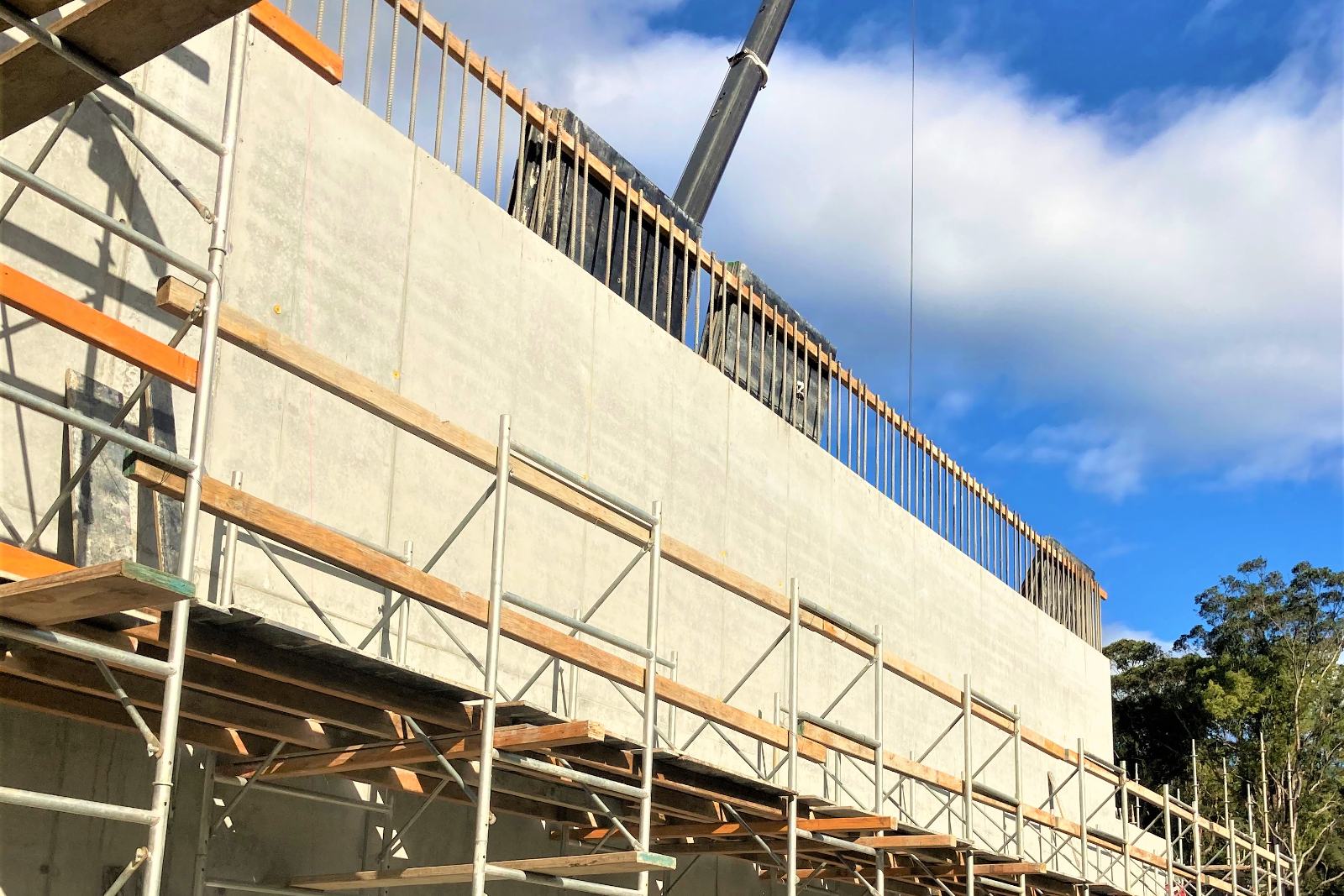 Abutment wall with scaffold and crane boom overhead