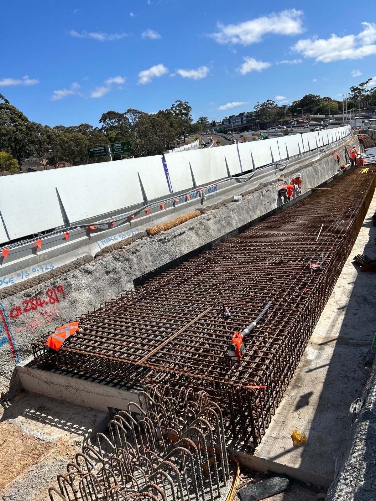 Crew fixing the deck reinforcement mat alongside the precast barrier